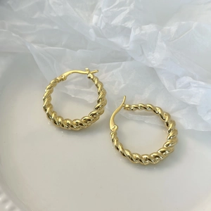 Detailed close-up of French vintage gold twisted hoop earrings on white ceramic base