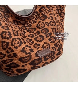 Close-up of leopard print canvas tote with brown leather logo tag and handle details