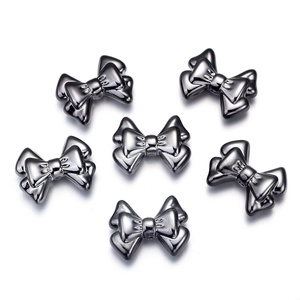 Macro detail of six metallic bow-shaped charms in a glossy gunmetal finish on white back