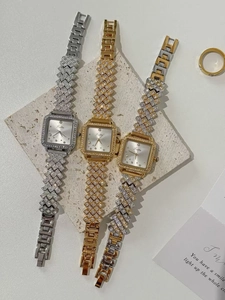 Detailed view of three luxury square watches with rhinestones on stone background