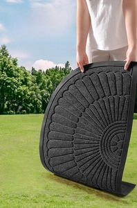 Outdoor semi-circle black rubber floor mat with sand-removal grooves on a green lawn