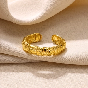 Detailed macro view of a gold-plated adjustable ring featuring embossed floral patterns