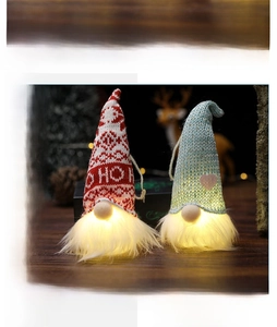 Close-up of glowing faceless Christmas gnome ornaments with warm LED light in beard