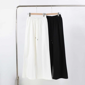 Detail of loose-fit drawstring waist on black and white wide-leg sweatpants