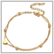 Detail of 18K gold stainless steel layered anklet featuring heart pendant and bead charms
