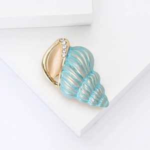Elegant gold and blue conch brooch with rhinestone accents and opal on white background