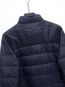 Close-up of horizontal quilting and fabric texture on a navy blue padded winter coat
