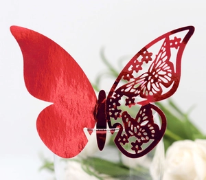 Macro view of metallic red hollow butterfly paper cards on a wine glass rim