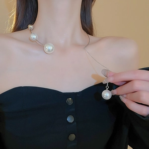 Close-up of irregular pearl necklace on neck featuring silver metallic curve and chain