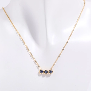 Collier doré avec trois pendentifs en zircon bleu présenté sur un buste de mannequin