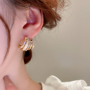 Close-up of a model wearing a gold C-shaped earring with multi-layer micro-inlaid rhinestones