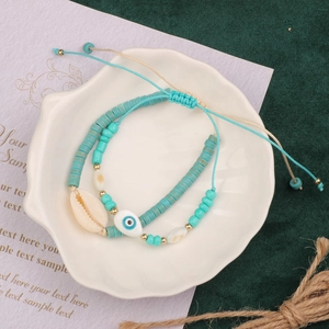 Detail of turquoise beaded bracelets with shell and evil eye charms in a shell dish