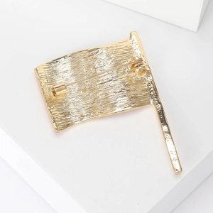 Golden metal brooch with American flag waving shape and detailed textured surface