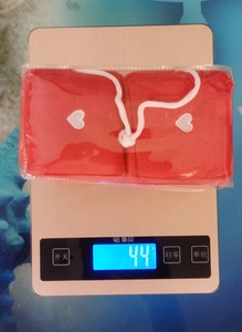 Detailed view of red plush heart car pendants in packaging weighing 44g on a scale