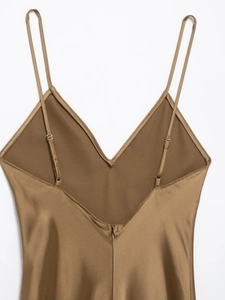 Detail of elegant gold satin dress featuring a deep V-back design and thin straps