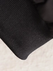 Gros plan des poignets en tricot côtelé noir et de l'ourlet de la veste de baseball