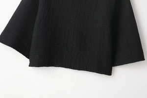 Close-up of fine knitted fabric texture and flat stitched hem on black knit cardigan