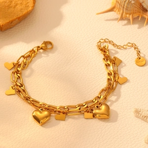 Double-layered 18k gold plated heart charm bracelet with Ssteal logo on leather background