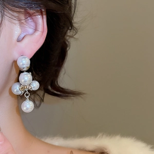 Dettaglio di orecchini di perle indossati da una modella con un design floreale vintage