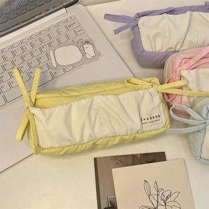 Detail of yellow fabric pencil case with bow tie and minimalist Sozakka brand label