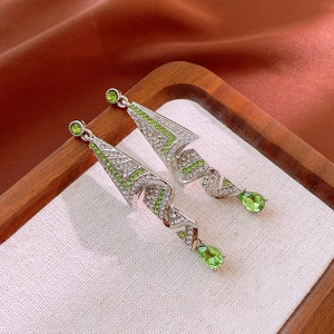 Macro shot of silver drop earrings with emerald green crystals and sparkling rhinestones