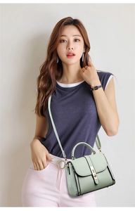 Detail of mint green crossbody bag with golden metal clasp shown on a model