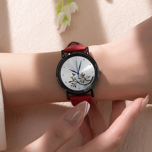 Detail of a floral dial watch with red leather strap shown on a woman wrist