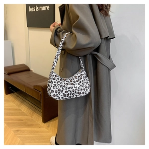 Détail d'un sac sous les bras chic en forme de croissant avec imprimé léopard porté par un mannequin