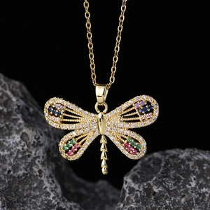 Macro shot of dragonfly pendant with multicolored zircons on a gold-plated chain