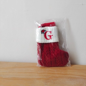 Close-up of a red knit Christmas stocking with white cuff and red embroidered letter G