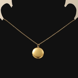 Detailed view of polished golden round locket pendant on a black display stand