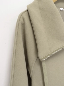 Detail of soft grey-green jacket featuring premium metal zipper and drawstring finish