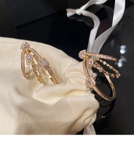 Macro shot of gold geometric earrings with pavé zircons on a beige textile background