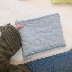 Detail of light blue quilted down clutch bag with soft floral embroidery and metal zipper