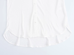 Detail of white textured fabric with elegant pearl buttons and curved hem design