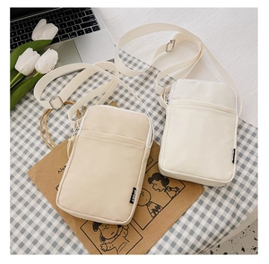 Flat lay of small corduroy crossbody bags in beige and white with SPORT labels