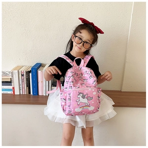 Detail of pink toddler backpack with unicorn prints and side mesh pockets shown on a girl