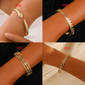 Detail view of four gold plated titanium steel bracelets featuring snake and leaf patterns