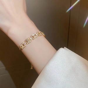 Gros plan d'un bracelet doré à maillons en H avec zircons sur le poignet d'un mannequin