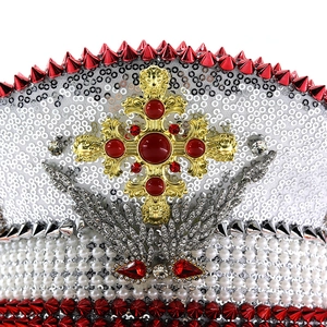 Close-up of sequin captain hat featuring a gold cross, red gems, and silver wings details