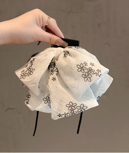 Détail de la pince à cheveux à fleurs blanches avec d'élégants rubans noirs fluides