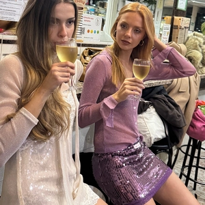 Dettaglio camicia in rete di paillettes viola e abito di pizzo beige alla festa