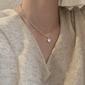 Close-up of double layer silver necklace with heart pendant and faceted gemstone inlay