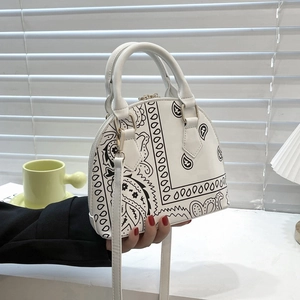 Detail of white shell handbag featuring black bandana print and gold metal accents