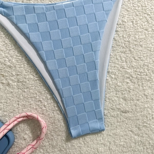 Detailed close-up of light blue checkerboard textured bikini bottom with premium fabric finish