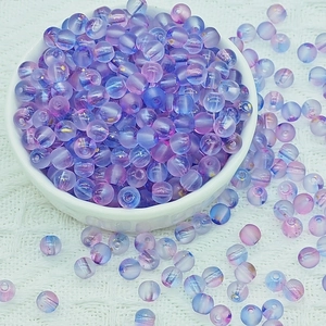 Detailed macro of 6mm purple and blue frosted glass beads with gold foil in a white bowl