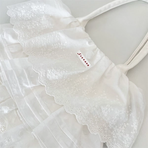 Dettaglio borsa tote in cotone bianco con balze in pizzo a strati e ricami floreali