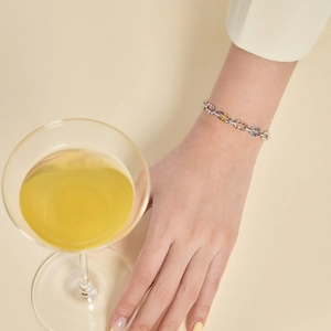 Detailed shot of a silver tennis bracelet with colorful square zircons worn on a female wrist