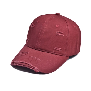 Close-up of distressed vintage baseball cap showing frayed edges and burgundy cotton fabric