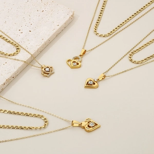Detail view of layered gold heart and crown pendants with sparkling rhinestones set